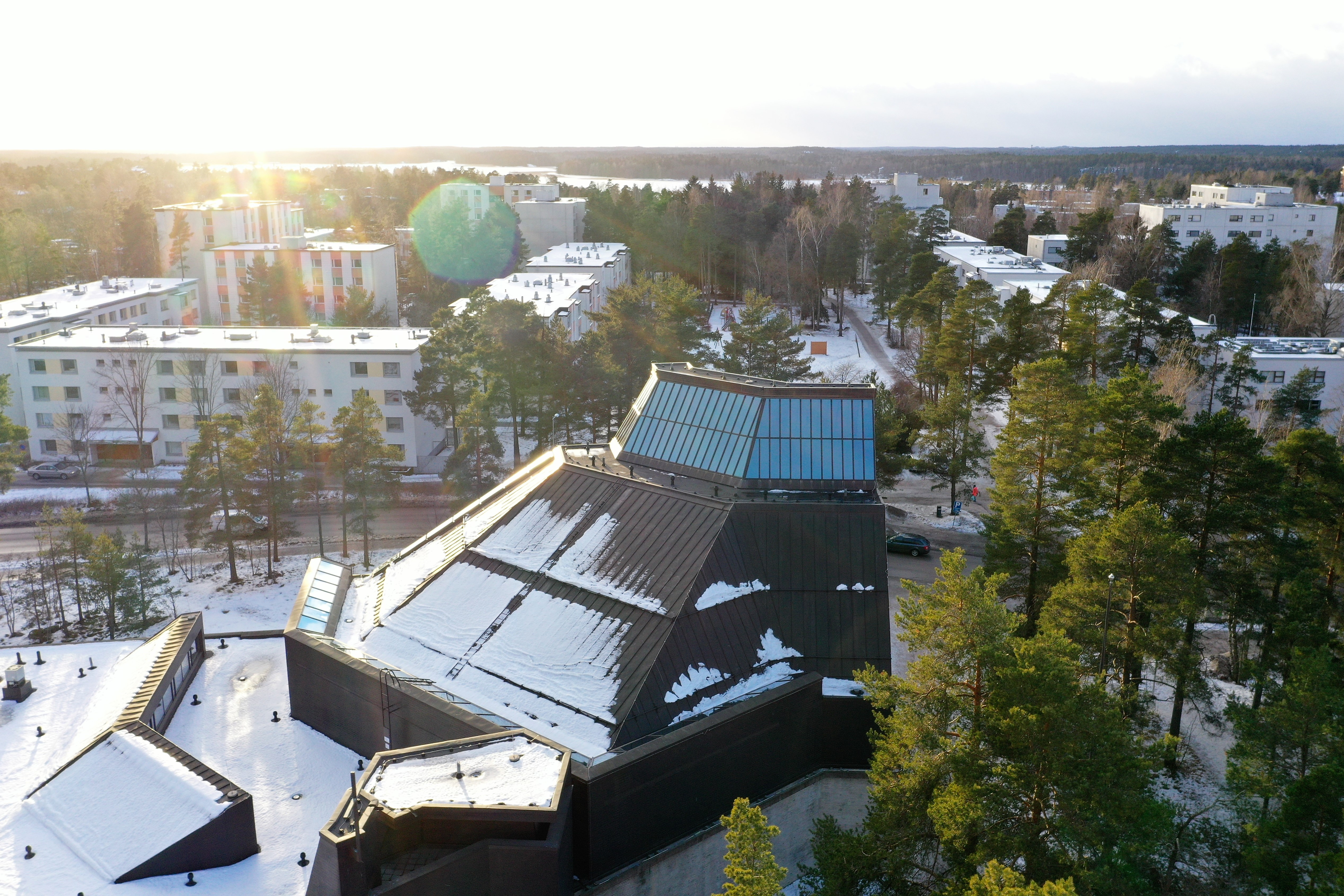 Espoonlahden kirkko lumipeitteen alla. Aurinko paistaa kirkkaasti.