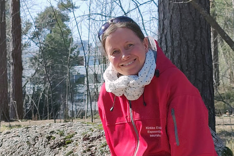 Ulkokuvassa isolla kivellä istuu punatakkinen Katriina Vilkman. Aurinko paistaa kirkkaasti. Taustalla metsä...