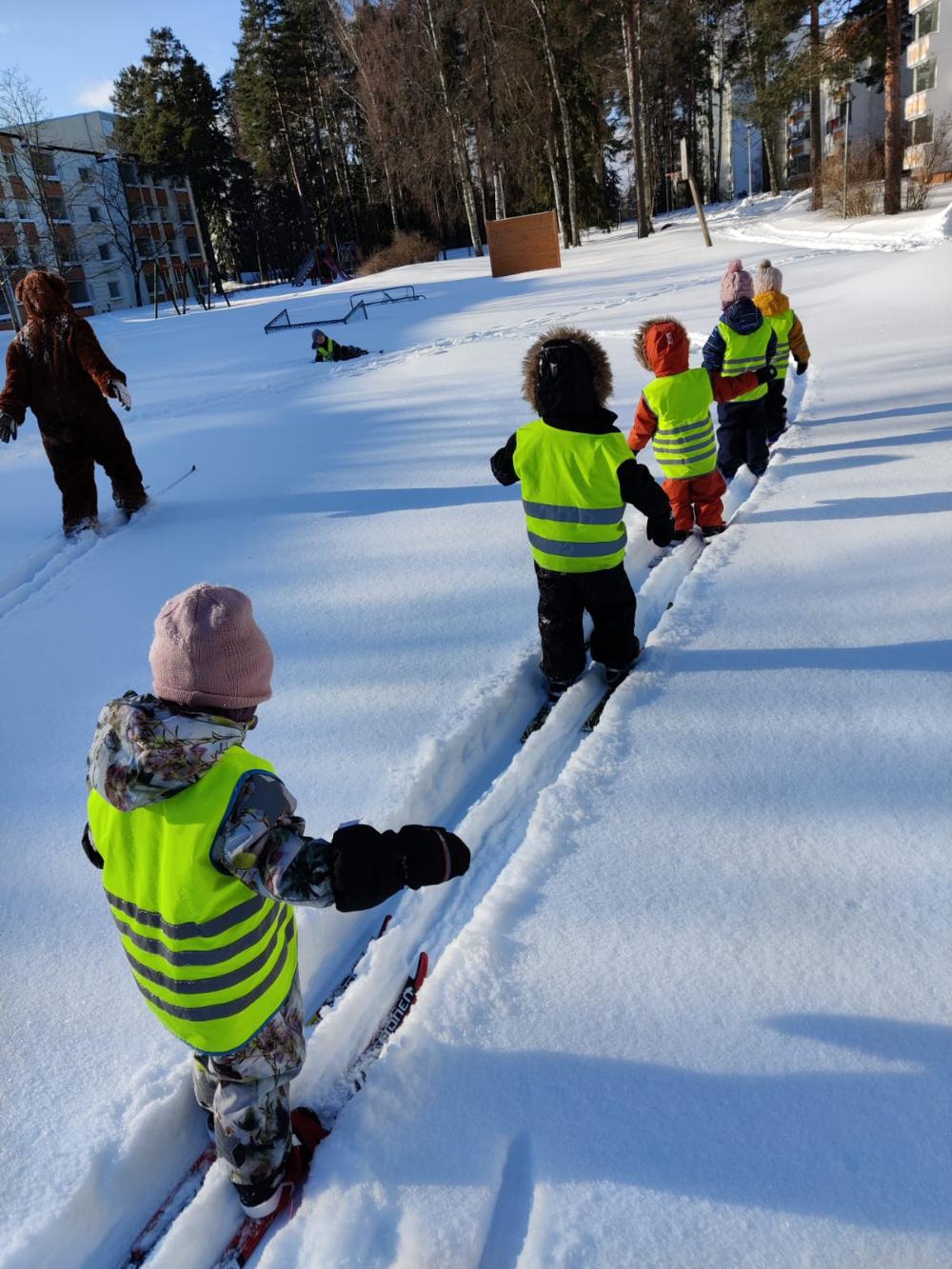 Päiväkerholaiset hiihtämässä lumisessa maastossa.