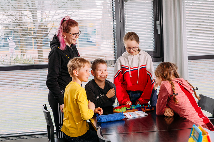 lapset ja aikuinen pelaavat iloisesti lautapelejä