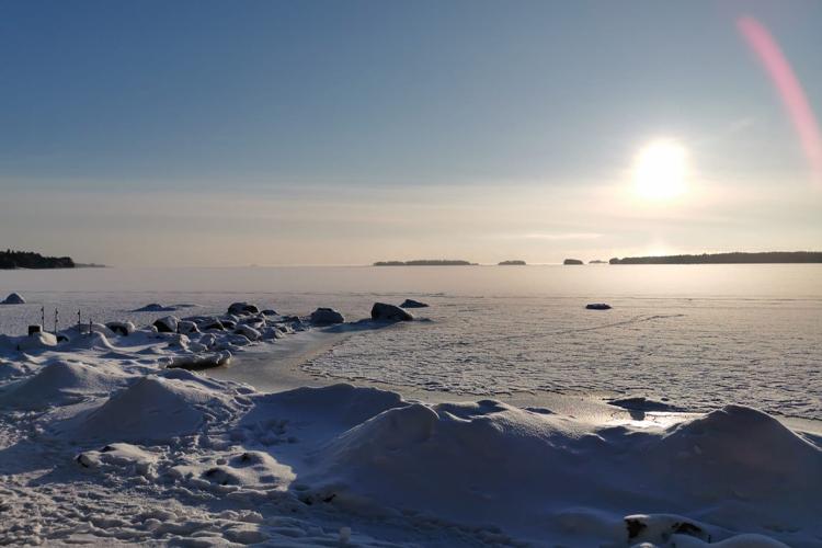 Kuvassa lumisen ja jäisen talvinen merenrantamaisema auringonpaisteessa.