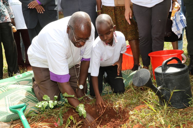 Tansanialainen piispa istuttamassa puuta yhdessä lapsen kanssa.
