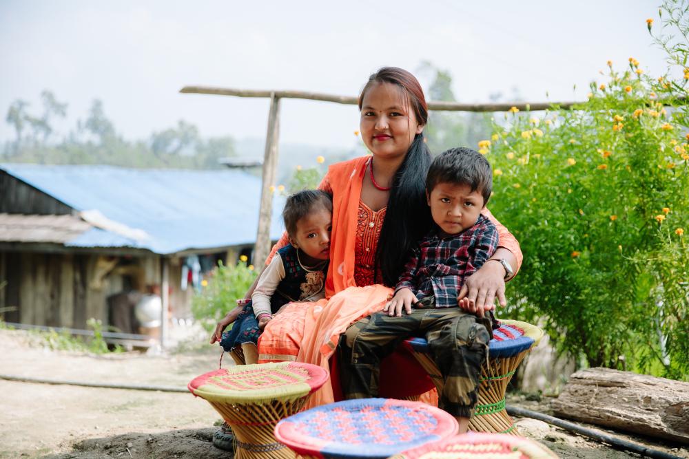 Nepalilainen äiti istuu kaksi lasta vierellään.