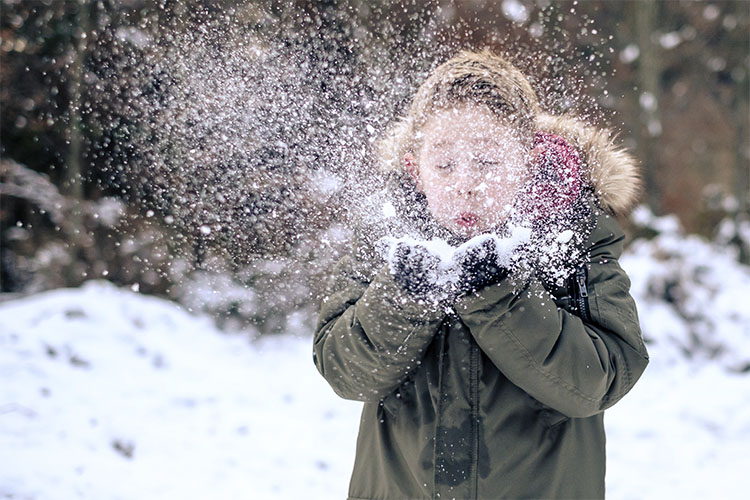 Tyttö puhaltaa lunta.