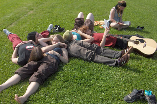 Nuoret makaavat auringossa nurmikolla kitaran kanssa.