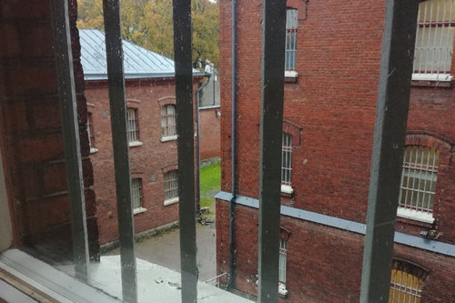Sörkän vankilan ikkunan kaltereiden takaa näkyy kaistale pihanurmea sateella.