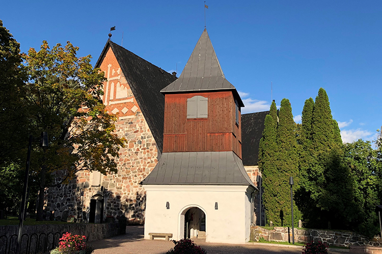 Espoon jylhä keskiaikainen kirkko ja sen kellotapuli lämpimässä kesävalossa