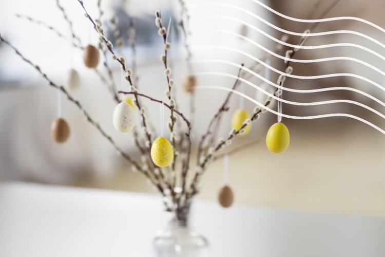 Värjätyillä munilla koristeltuja pajunoksia maljakossa pöydällä. Kuva on luotu Adobe Fireflylla teköälyn avulla.