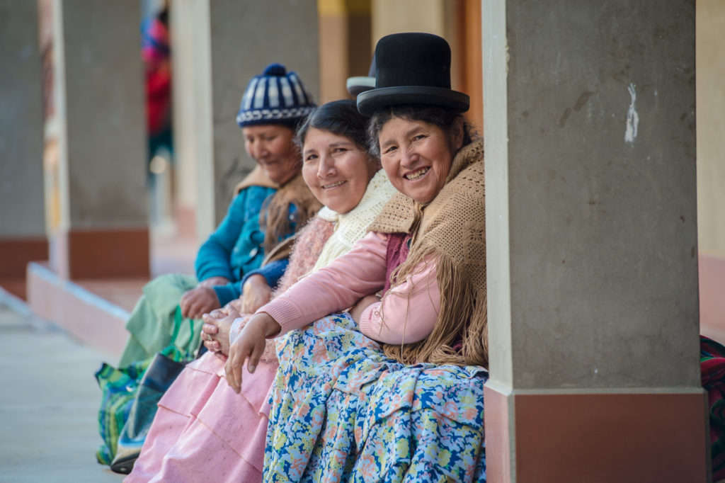 Bolivialaisia naisia istumassa talon edustalla.