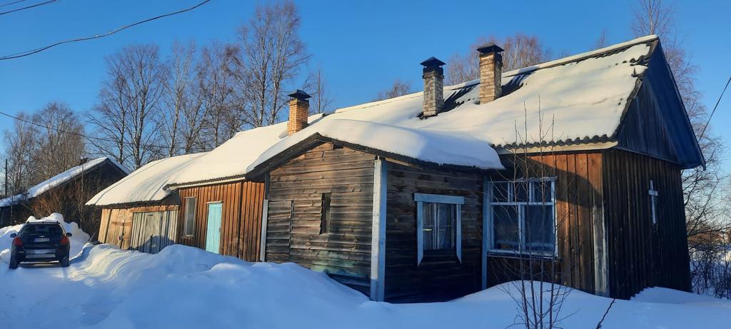 Karjalainen puinen seurakuntatalo lumisessa maisemassa.