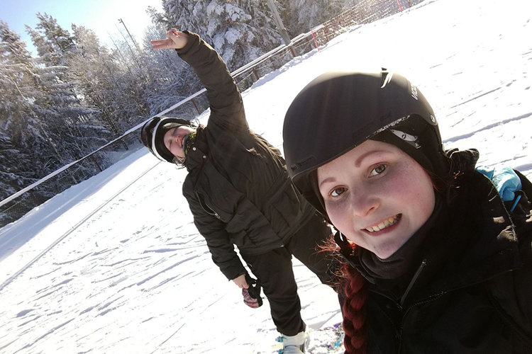 Kaksi nuorta laskettelurinteessä kypärät päässä talvi auringossa.