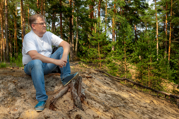 Mitä vielä? -ryhmä eläköityneille Mies istuu mesässä hiekkaisella harjulla ja katsoo näkymiä.