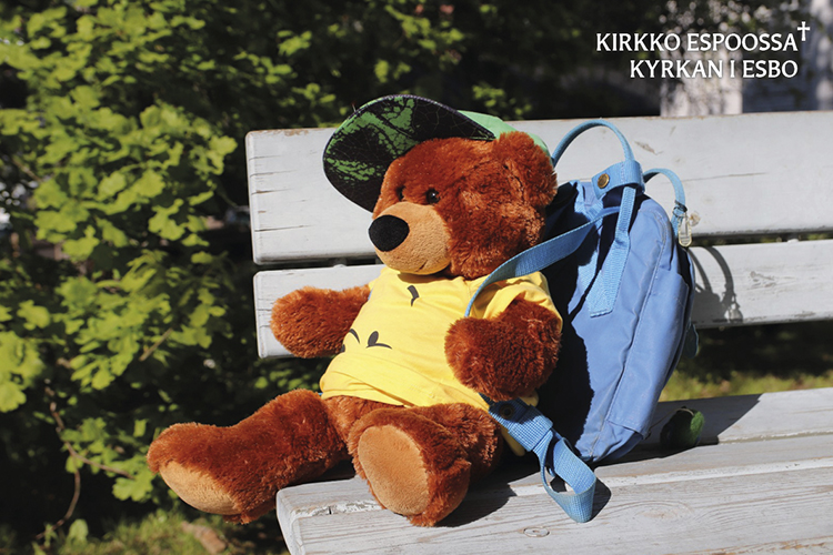 Koulutiensä aloittavien siunaaminen nalle istuu puiston penkillä, sillä on selässään koulureppu