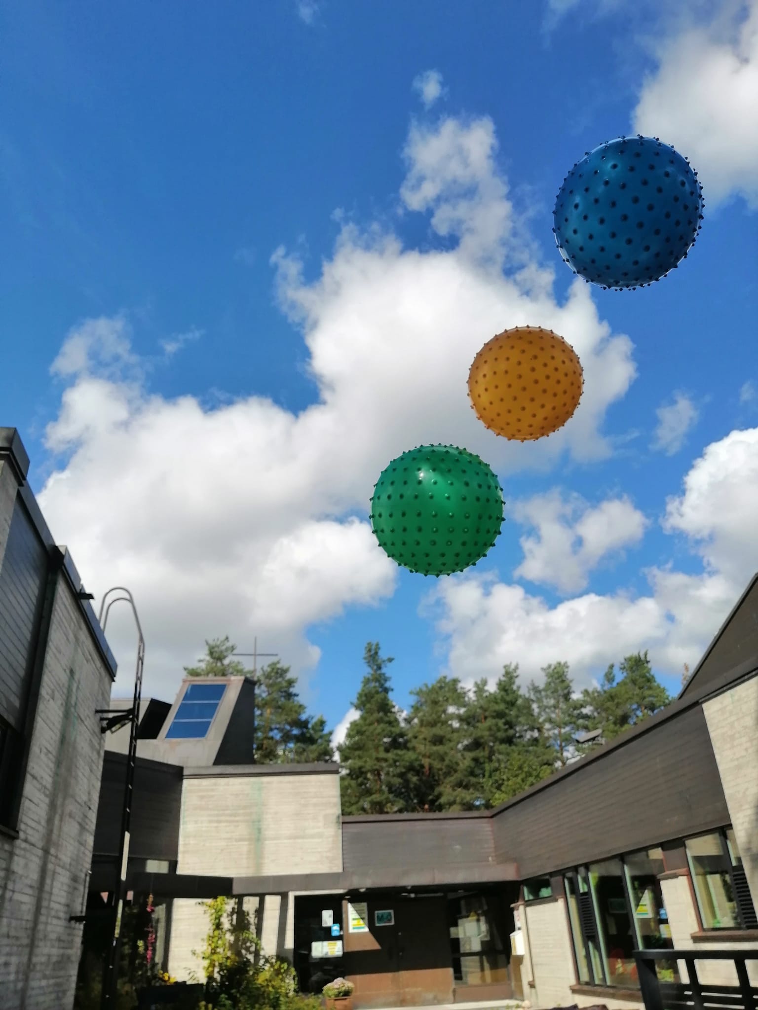 Kolme eri väristä palloa lentää ilmassa, taustalla Espoonlahden kirkkoa.