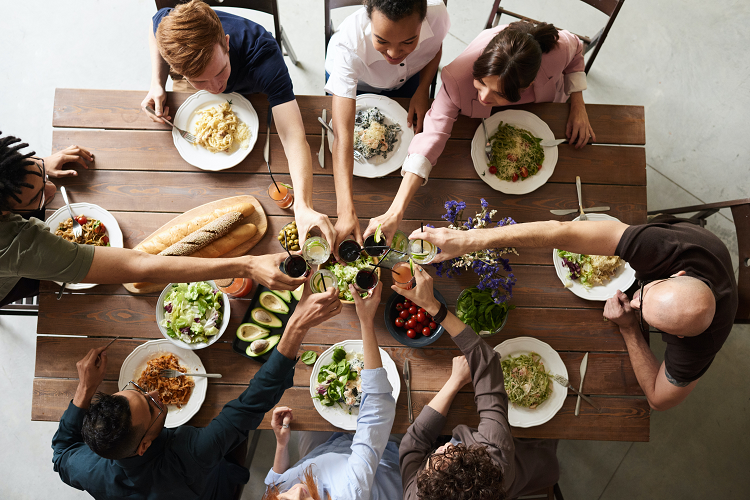 Kuvassa ruokapöydän ympärillä ihmisiä syömässä yhdessä.