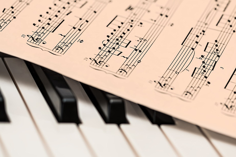 Pianon taikaa - espoolaisnuoret käynnistävät PianoEspoon juhlafestivaalin pianon koskettimet, joiden yli vinottain makaa nuottivihko