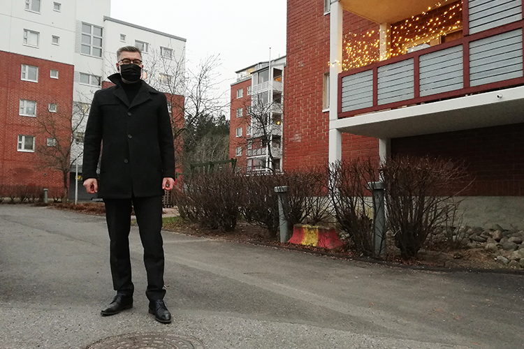 Kanttori Elja Puukko seisoo ulkona kerrostalon parvekkeen edessä talvivaatteissa maski kasvoillaan.