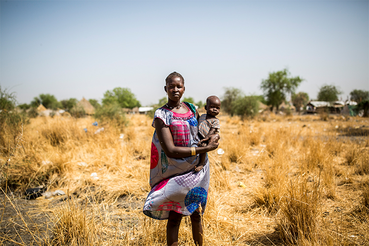 Kuvassa äiti ja lapsi Etelä-Sudanissa kotinsa edessä. 