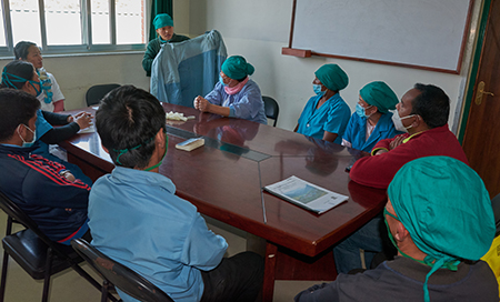 Kuva nepalilaisesta sairaalasta, jossa koulutetaan henkilökuntaa suojavarusteiden käyttöön.