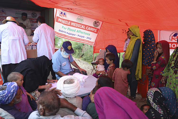 Kuvassa on apua odottavia eri-ikäisiä ihmisiä lääkeklinikan teltassa. Kuva:Pakistan Partners Initiative