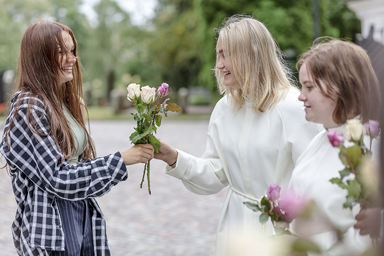 Isonen ojentaa onnittelukukkia rippikoululaisille.