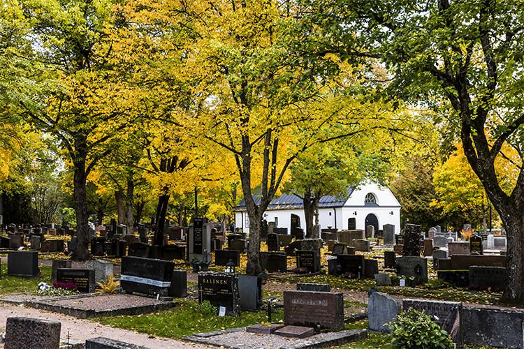 Kuvassa on Espoon Kirkon hautausmaa syksyn väreissä, taustalla Toimituskappeli.