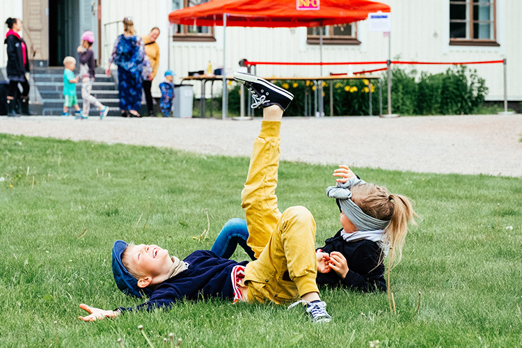 Kuvassa kaksi lasta leikkii nurmikolla.