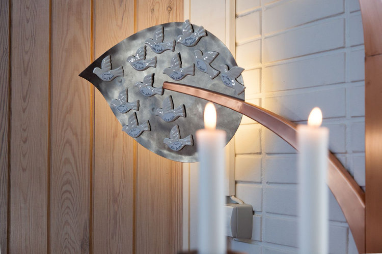 Soukan kappelin kastepuuhun kiinnitetään magneeteilla keraamisia kyyhkysiä, joissa lukee kastettujen lasten...