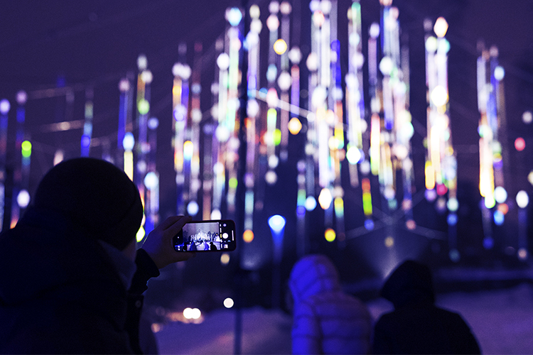 In picture there are people taking a picture in front of light installation.