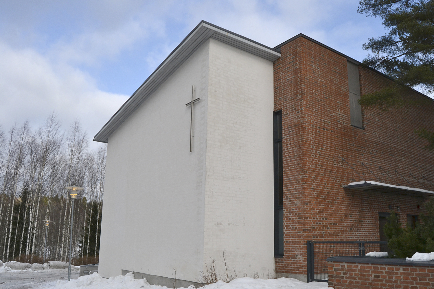 Moderni Nupurin kappeli valkoista ja punaista tiiltä, seinässä iso risti.