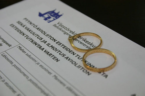 Kihlasormukset avioliiton esteiden tutkintalomakkeen päällä.
